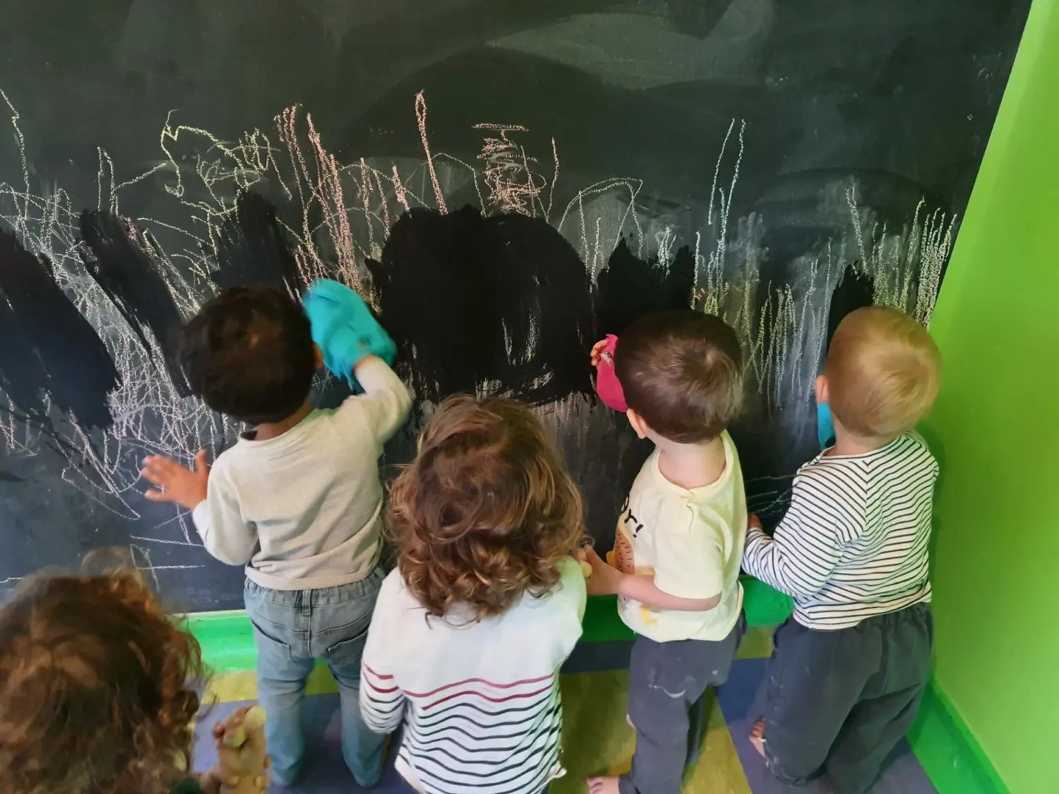 Enfants vus de dos dessinant ensemble à la craie