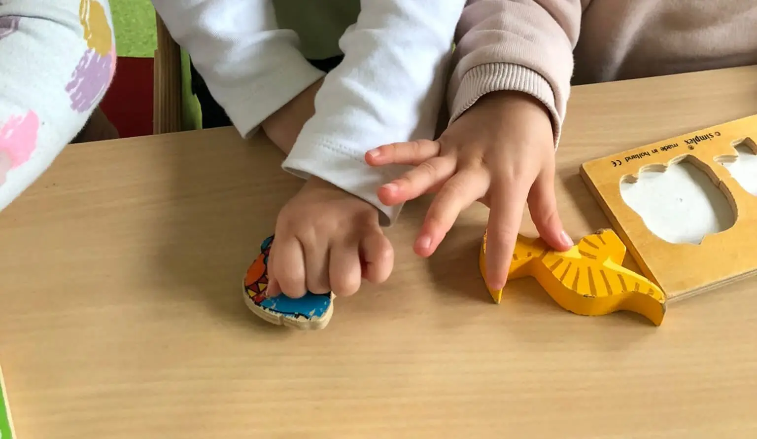Petites mains manipulant des formes colorées en bois