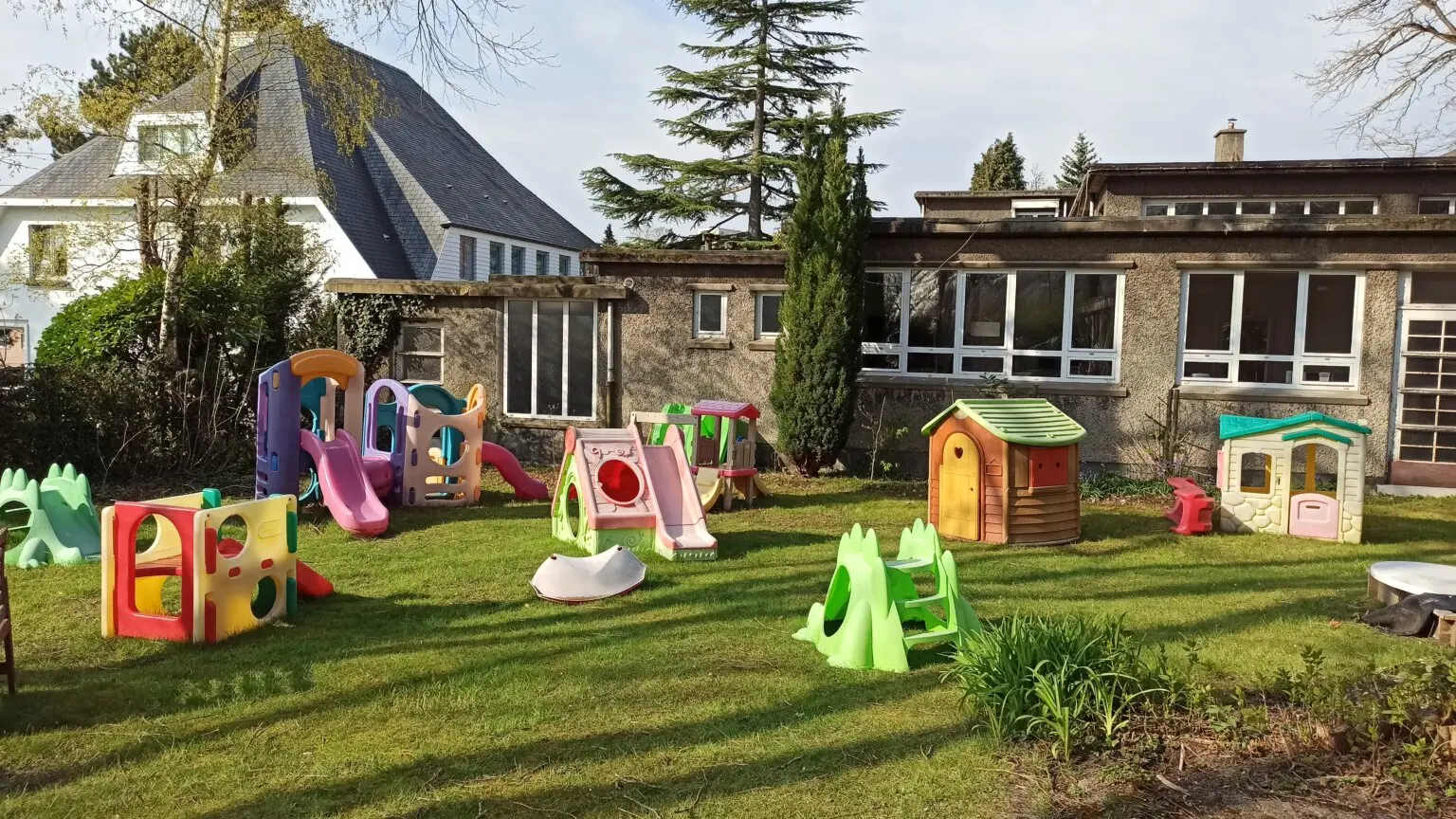 Grand jardin de la crèche aménagé avec des maisonnettes, des toboggans et des jeux colorés