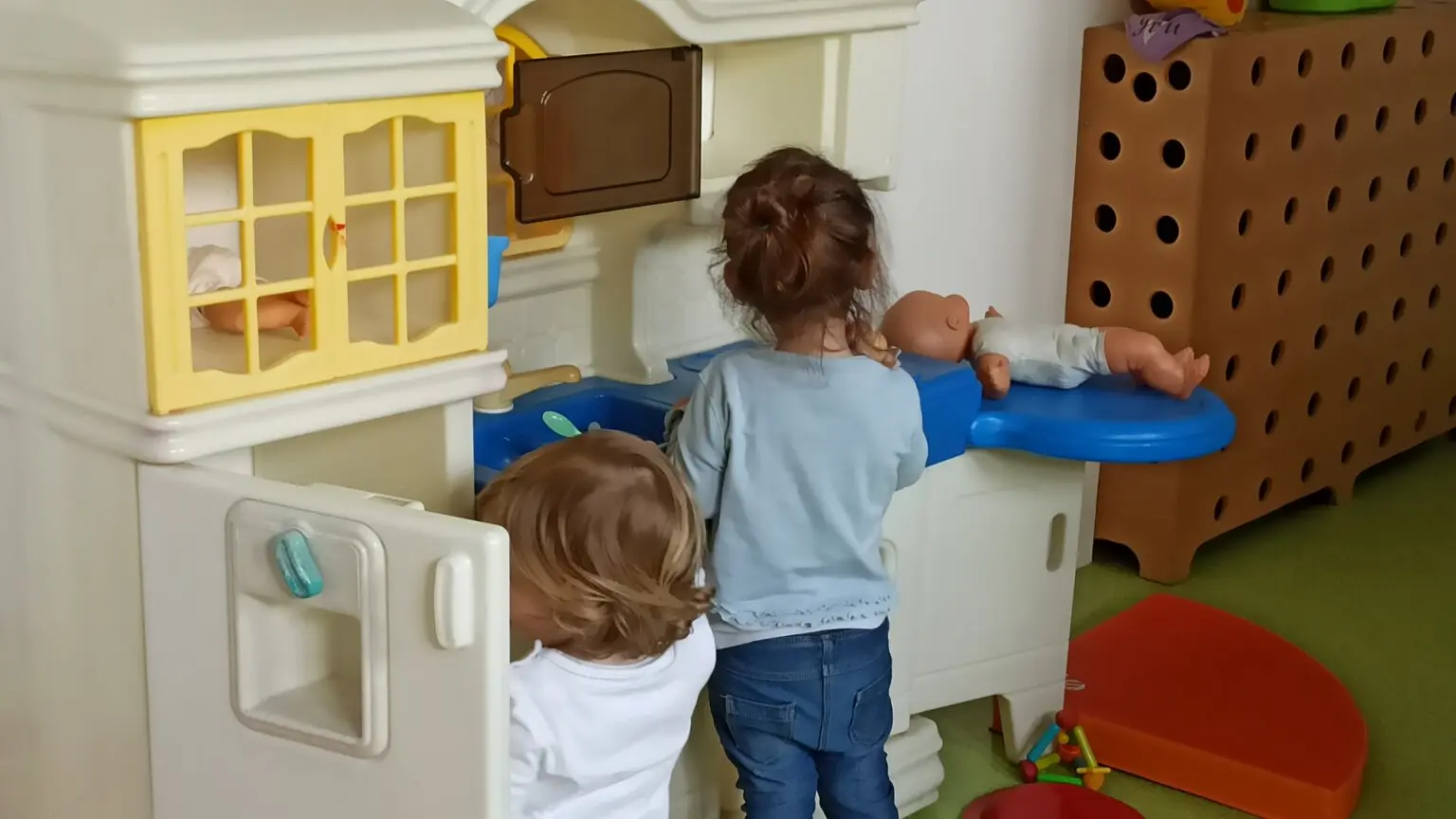 Deux enfants vus de dos jouant dans une petite cuisine