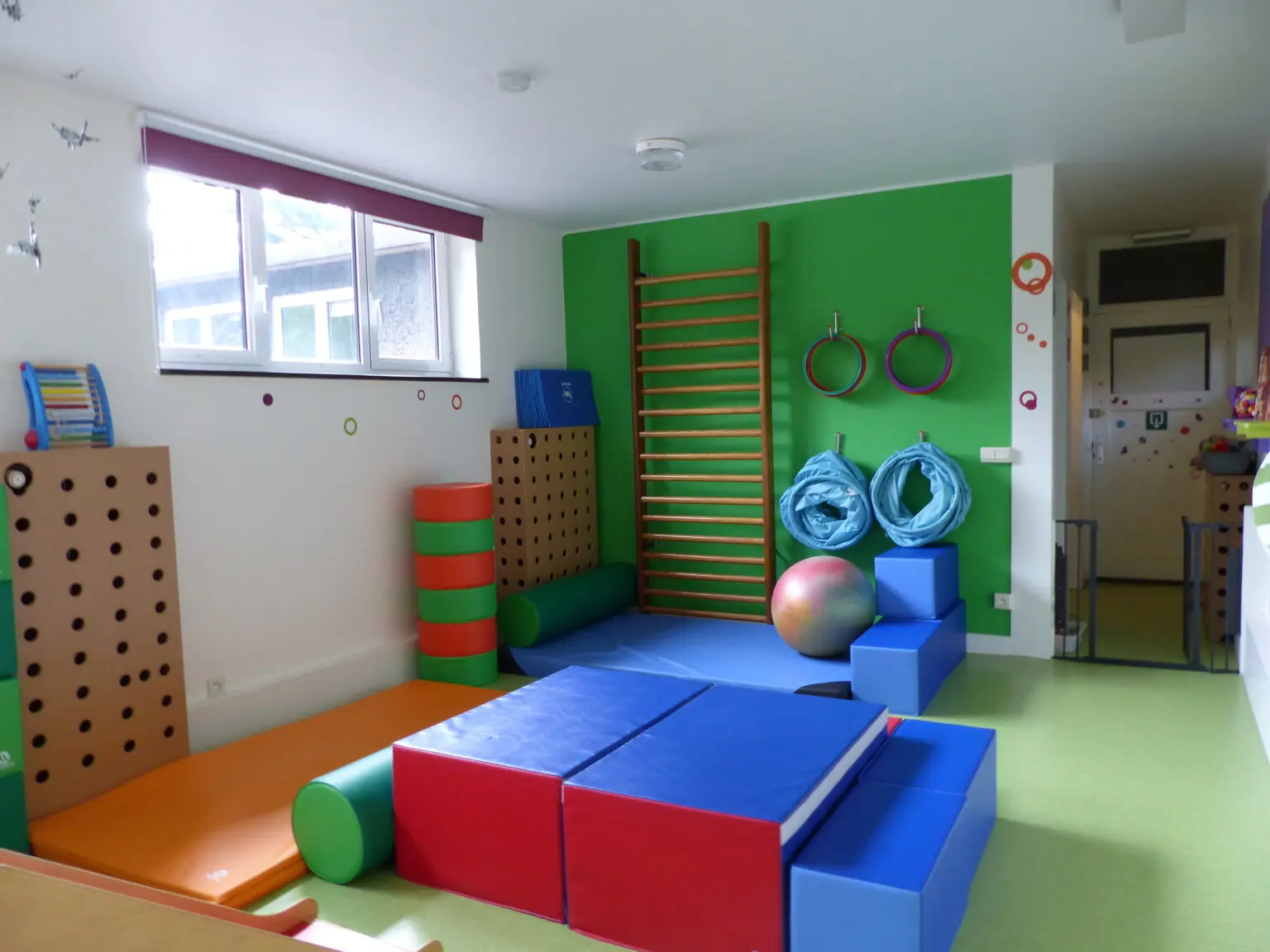 Salle de motricité avec tapis, modules et espaliers colorés